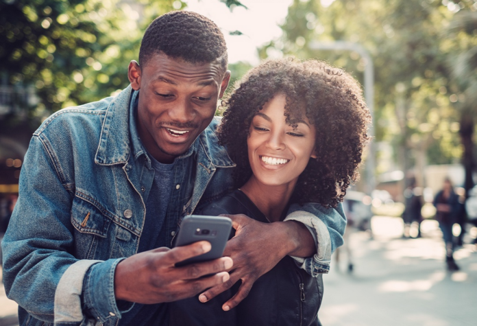A black couple looking at the phone. Phone insurance depiction.