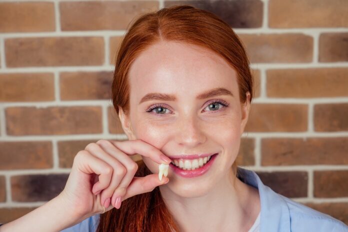 Redhead woman holding a wisdom tooth.