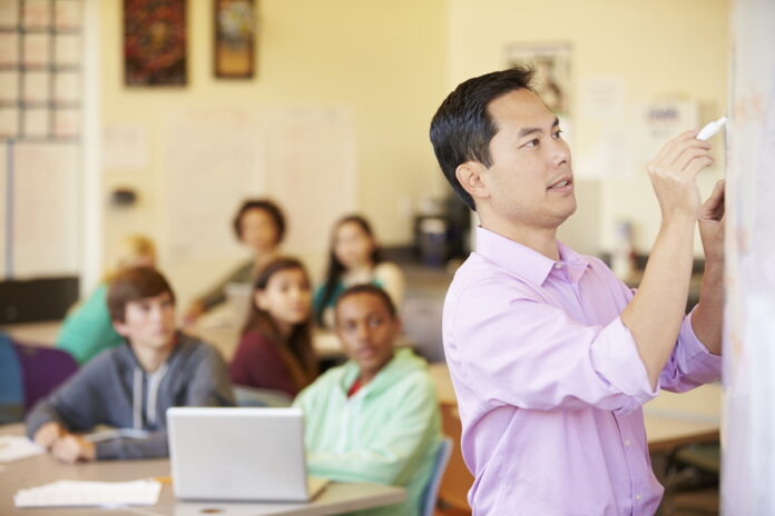 High School Students With Teacher In Class Using Laptops