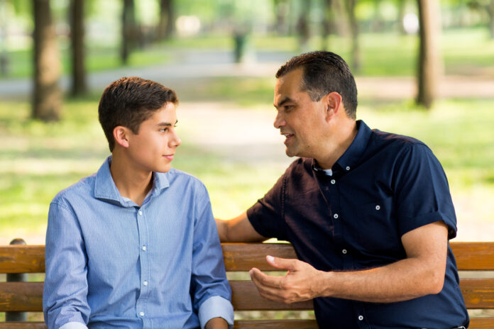 Father and son taking on a bench outdoors